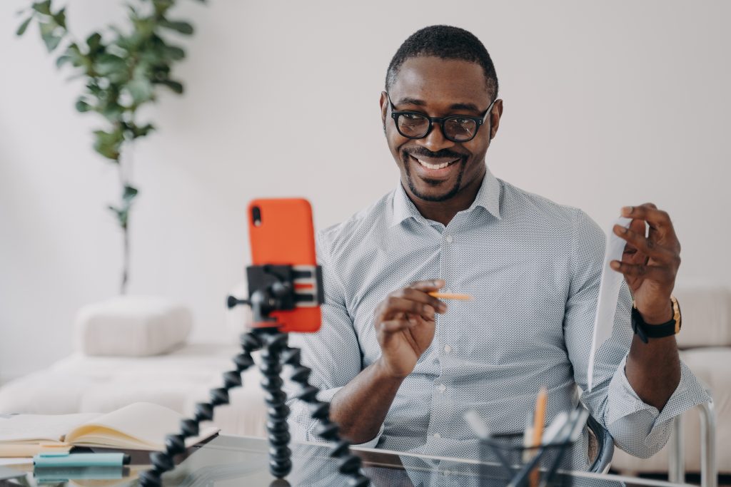 Smiling african american businessman presenting business data online by video call, using smartphone
